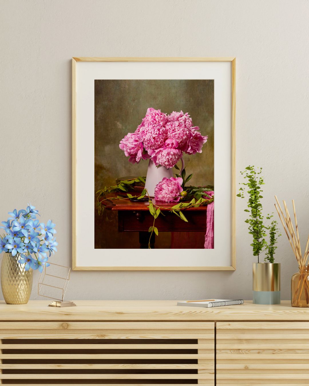 Image of a paper print with a white mat board and a natural wood frame on a wall above a cabinet