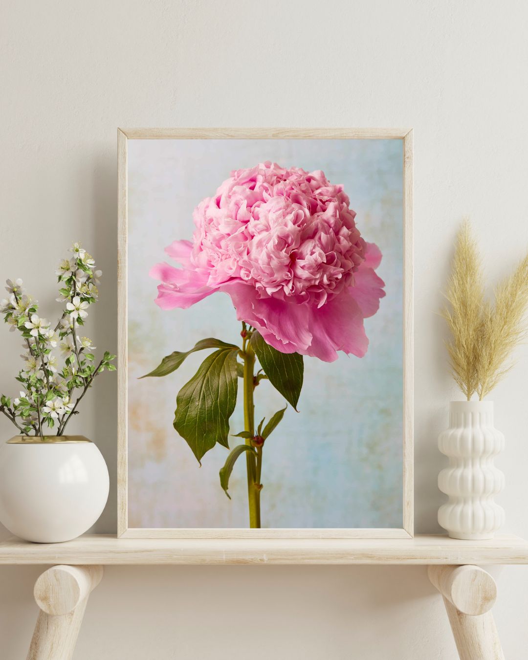 Canvas print in a light wood frame on a light wood colored shelf