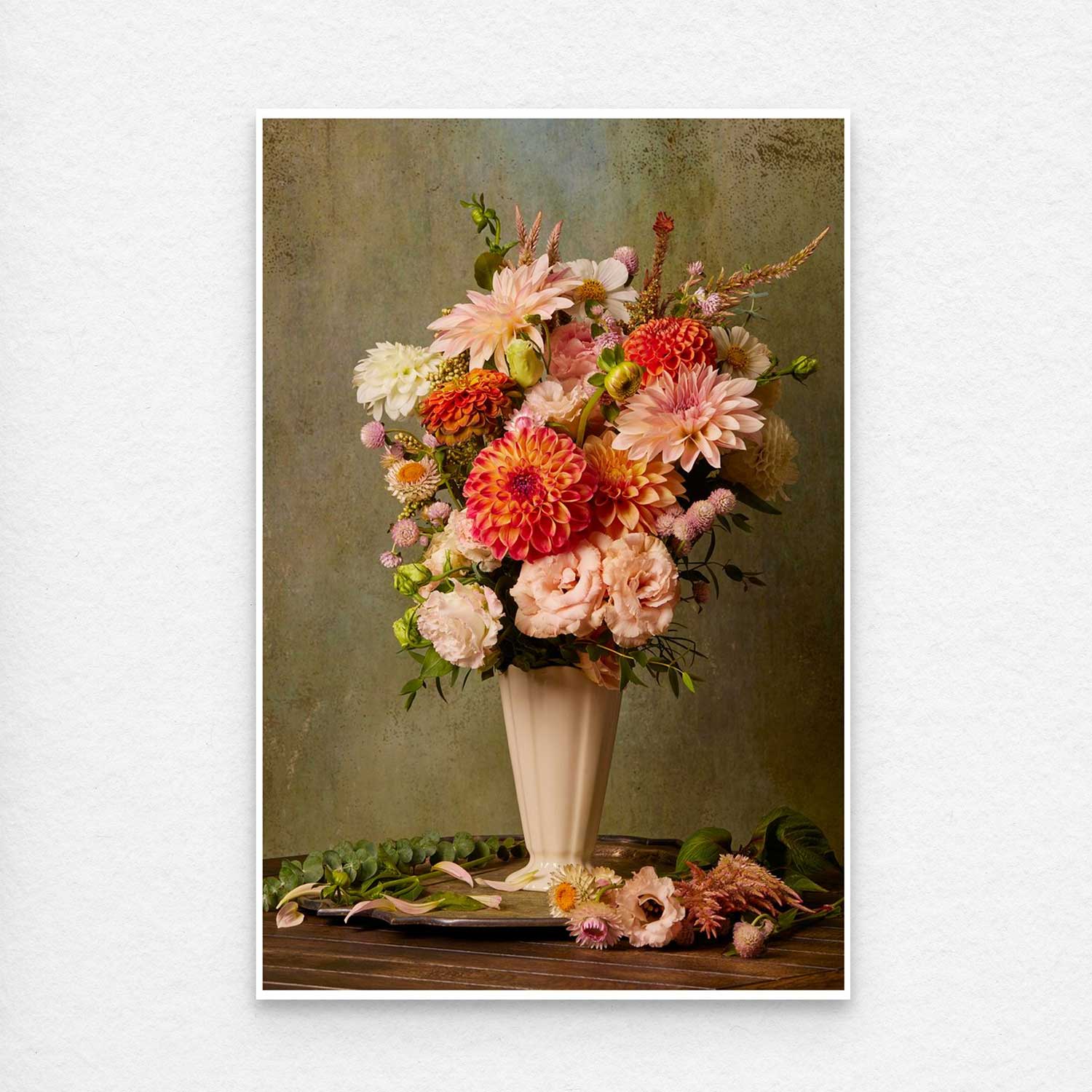 The Victorian Bouquet features a tall, elegant vase with lush, pink, orange, and cream flowers against a muted green backdrop. Extra blooms and greenery artistically adorn the base as canvas wall art for a harmonious display. The print has a small thin white border for easy framing.