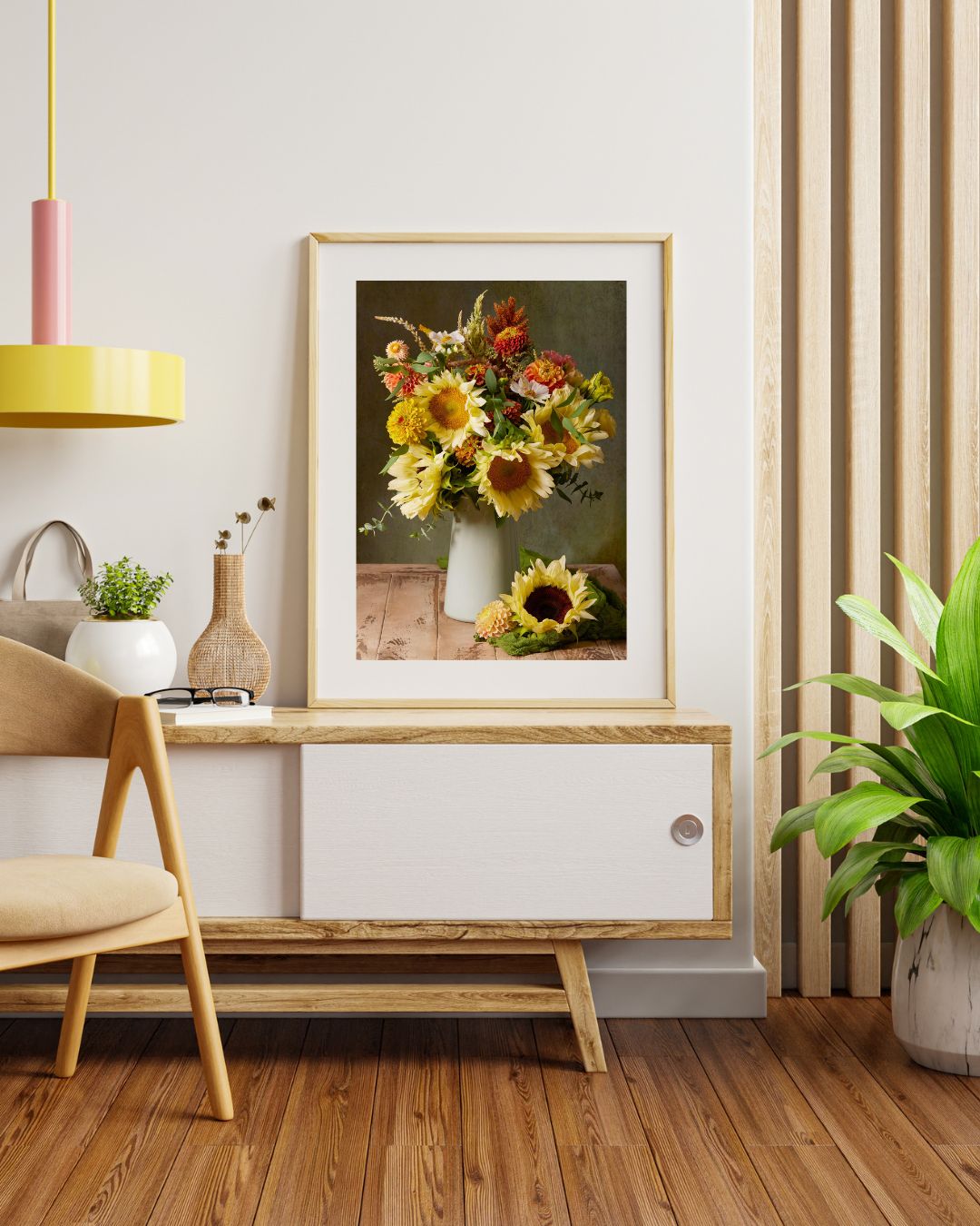 A stylish interior with a wooden floor showcases the Sunny Bouquet canvas wall art of sunflowers, complemented by a white sideboard, dried flowers in a vase, and a wooden chair. A green plant adds charm, while a yellow hanging lamp completes the chic décor elegantly.