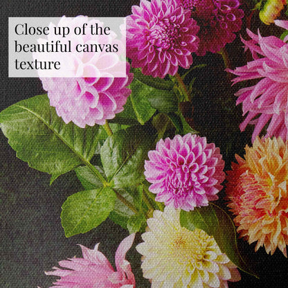 A close-up of the canvas from Garden's Grand Finale canvas wall art shows vibrant, detailed dahlias in pink, purple, and yellow hues with lush green leaves. A semi-transparent box in the top left corner reads Close up of the beautiful canvas texture.