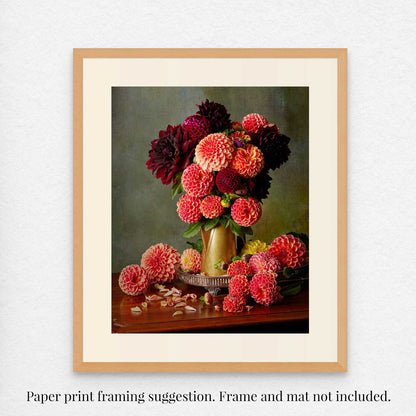 The Late Summer Glow art print features vibrant red and pink dahlias in a brass coffee pot on a wooden table surrounded by scattered petals. Shown with a simple mat and natural wood frame as a example. Frame and mat not included.