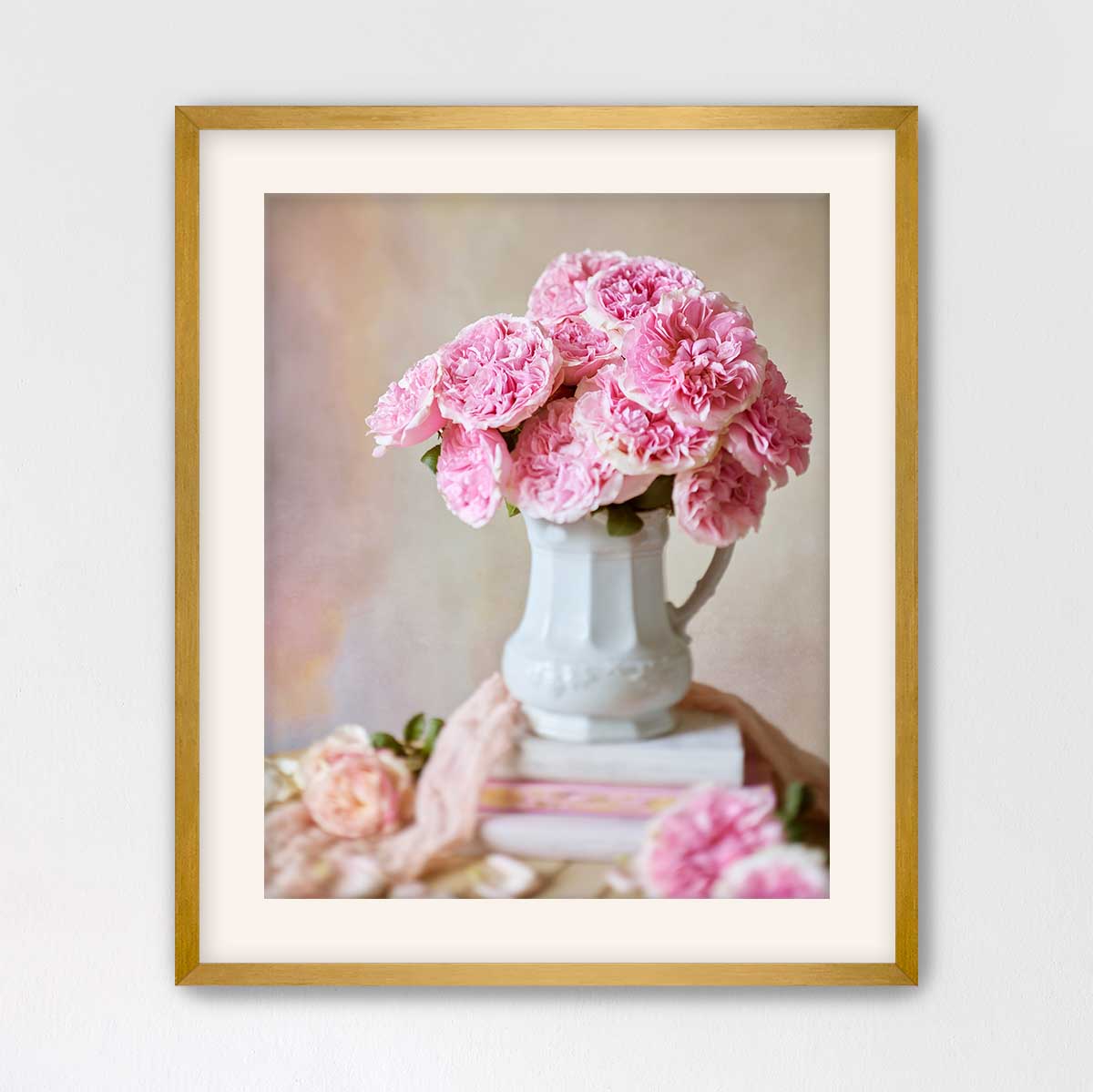 A white vase filled with pink flowers sits on top of a stack of books, creating a charming and elegant scene.