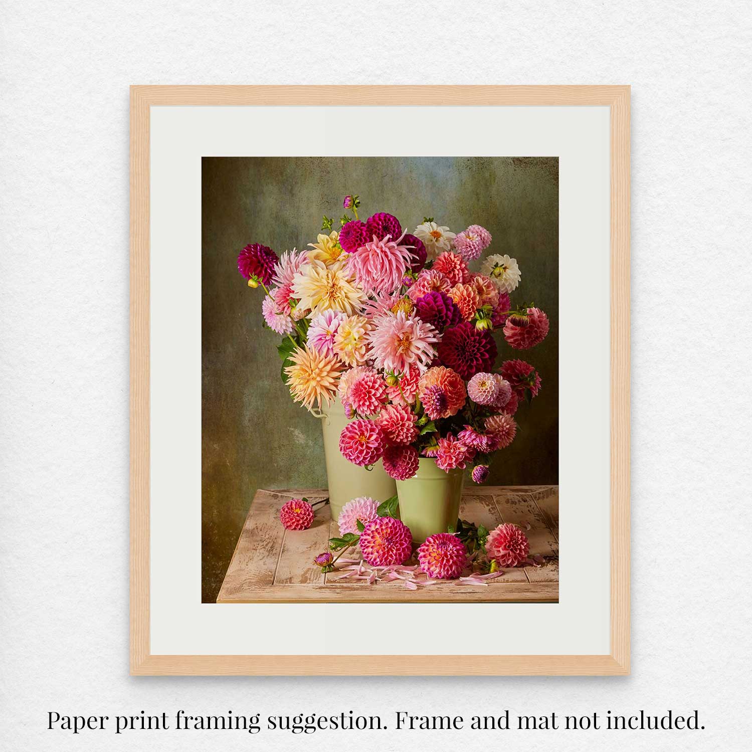 The Dahlia Harvest fine art paper print features vibrant pink, purple, and yellow dahlias in green vases with scattered flowers on a muted background. Caption: Framing suggestion. Frame and mat not included..