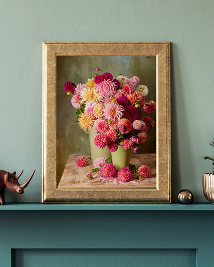 The Dahlia Harvest, showing vibrant dahlias in a green vase, framed in gold, adorns a teal mantel. Paired with a rhino figurine and potted plant.