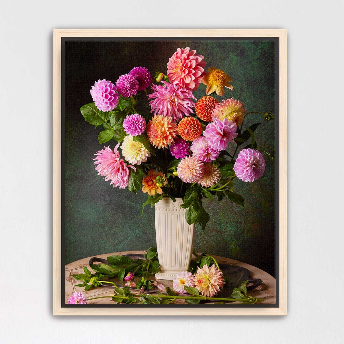 A bouquet of vibrant dahlias in a white vase, set against a dark green background.
