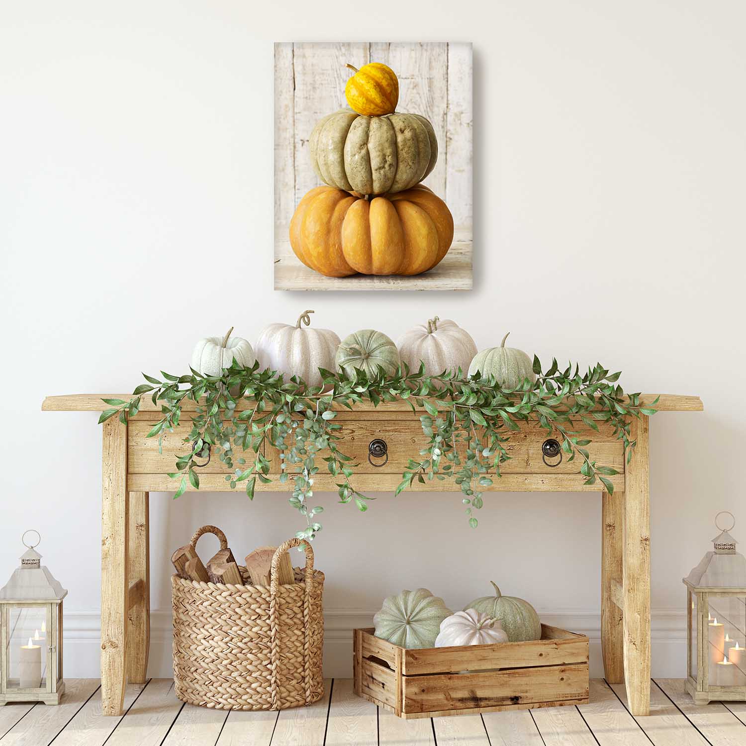 Decorative setup with pumpkins on a wooden console table against a white wall with a canvas print of 3 stacked pumpkins on the wall.