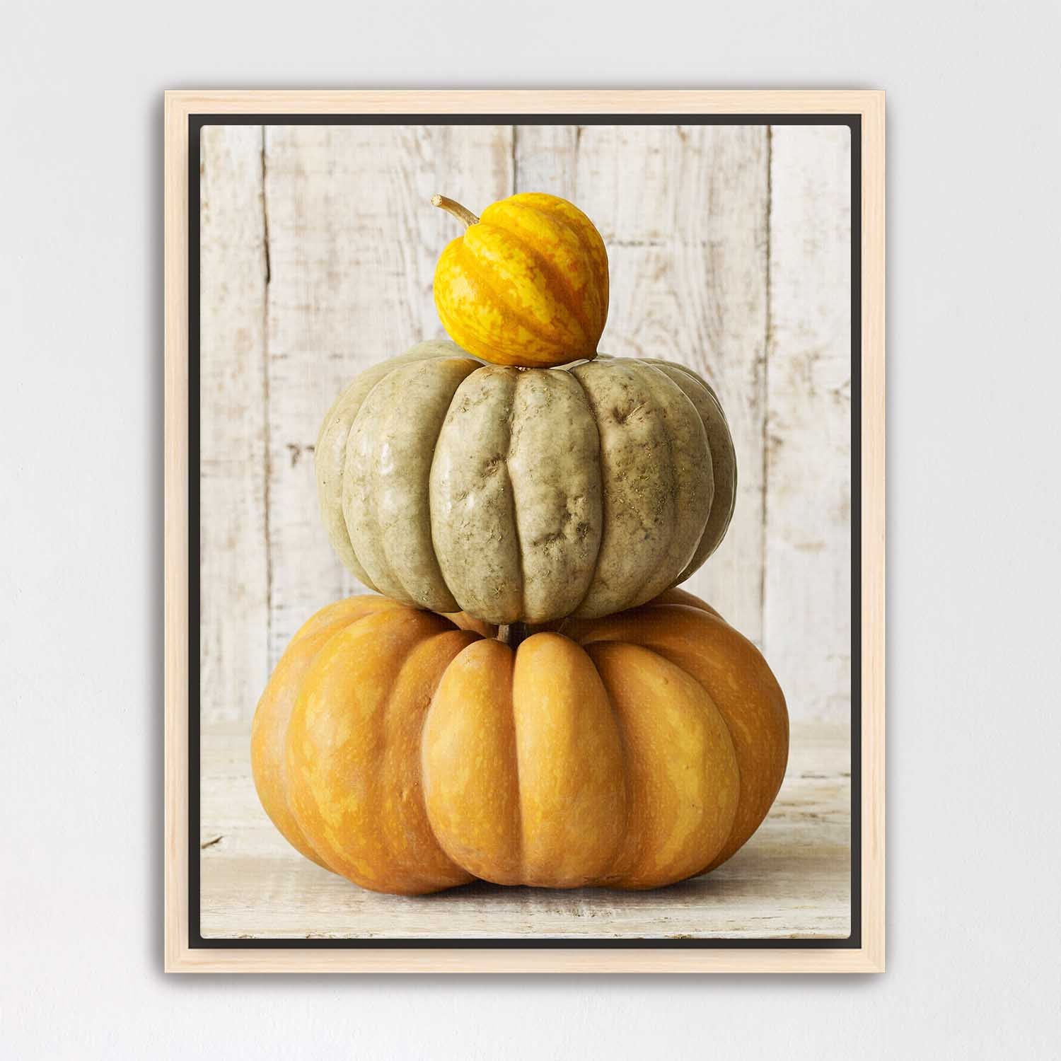 Maple framed canvas of stacked pumpkins on a wooden surface