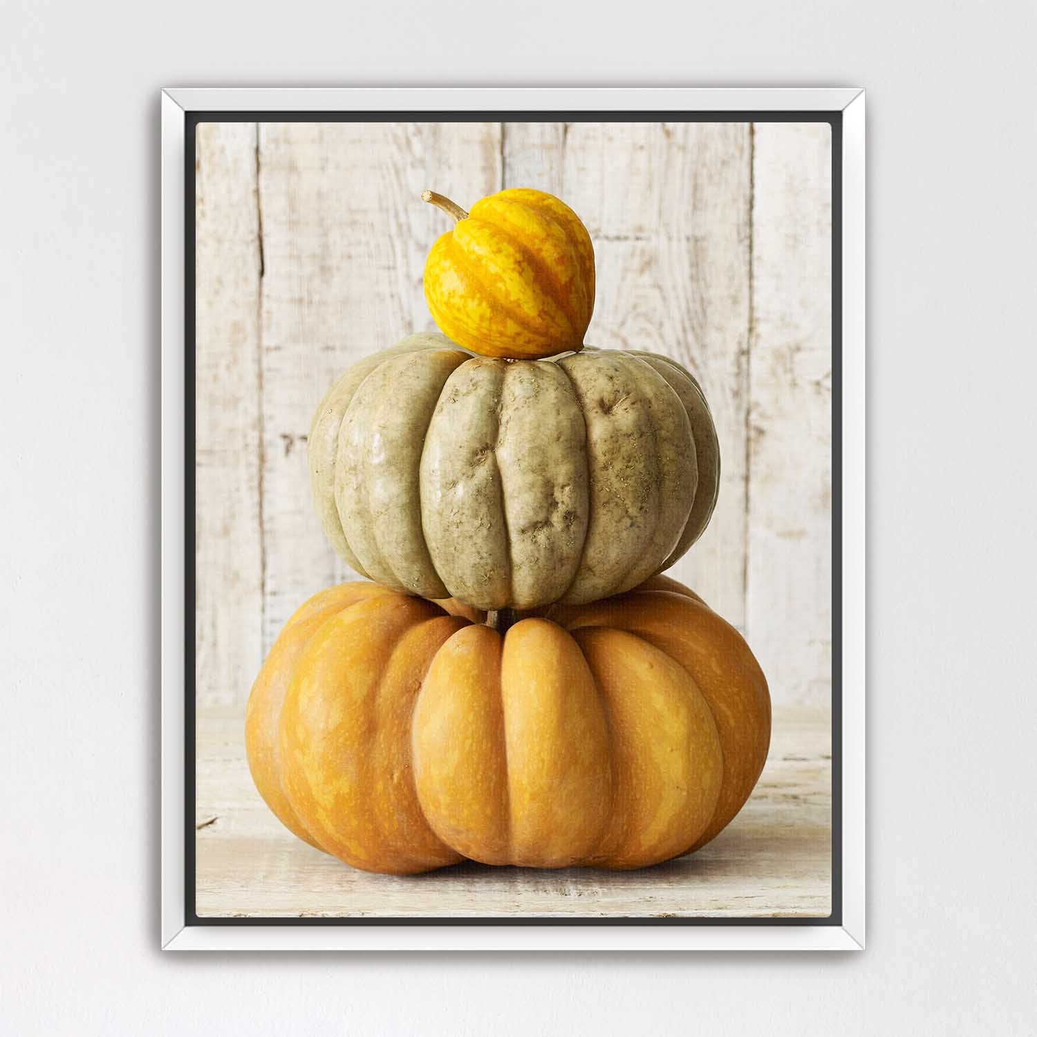 White Framed canvas of stacked pumpkins on a wooden surface