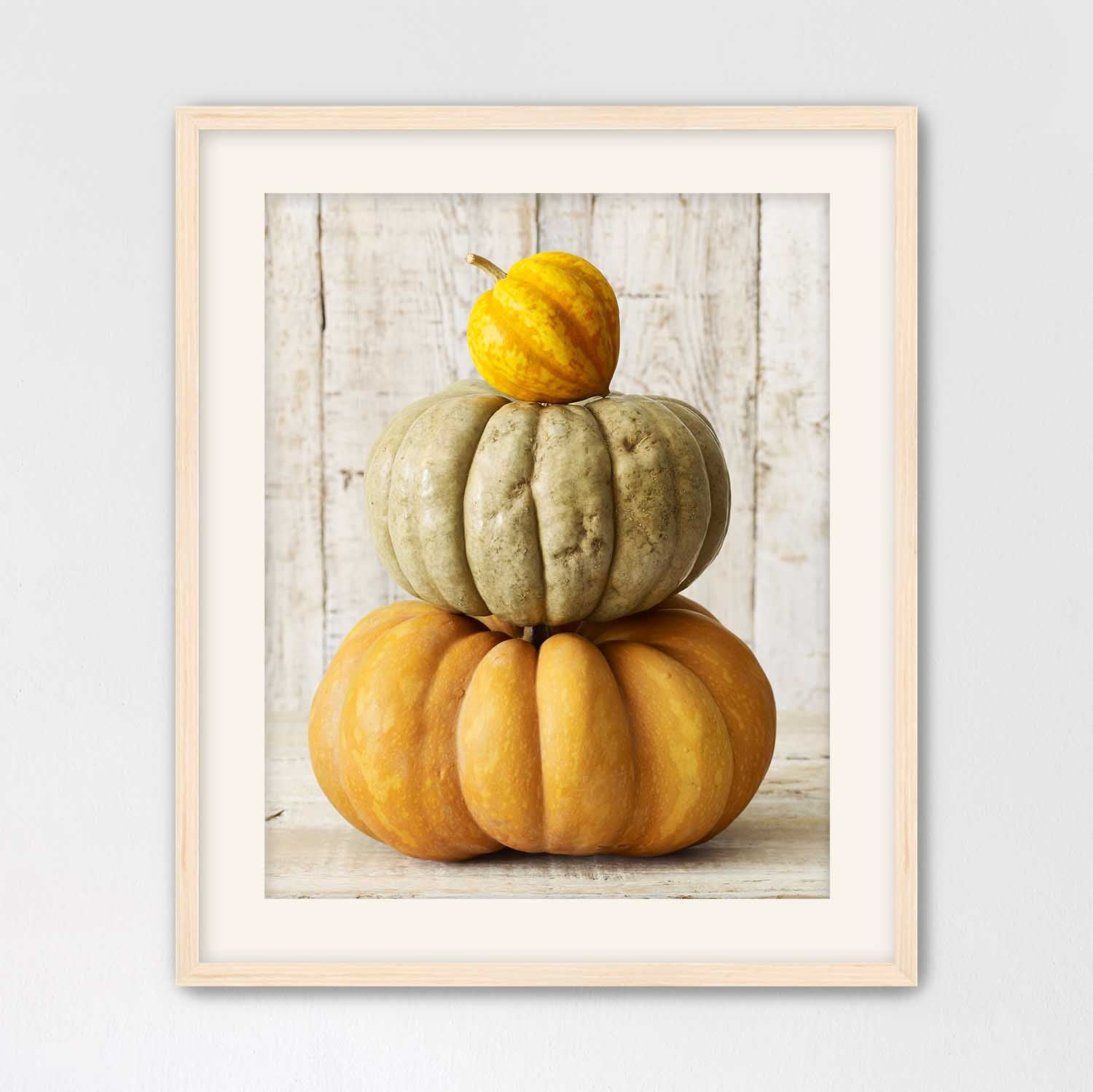 Maple framed photograph of three stacked pumpkins on a wooden surface