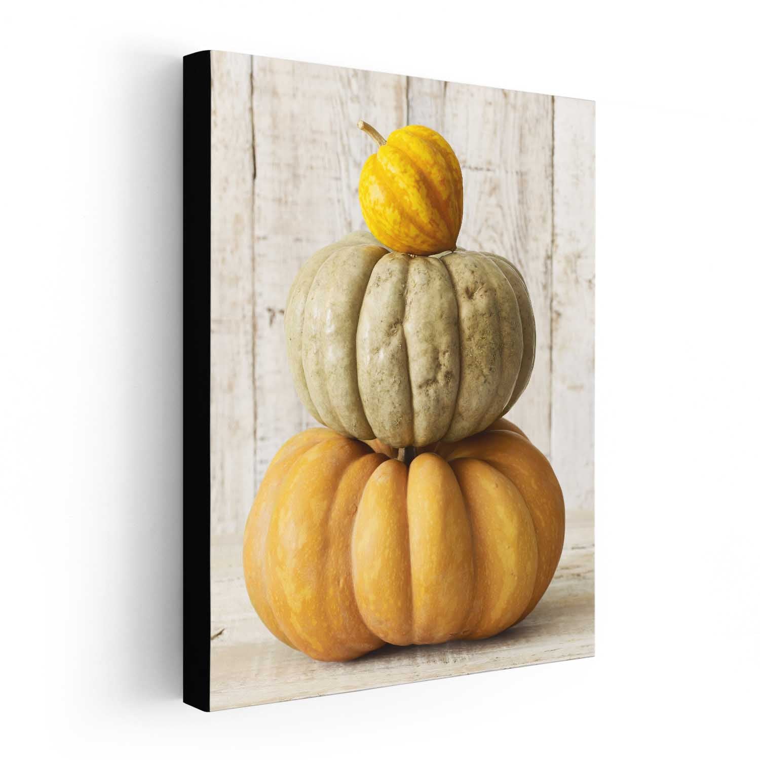 Canvas print of a stack of pumpkins on a wooden surface with a white background