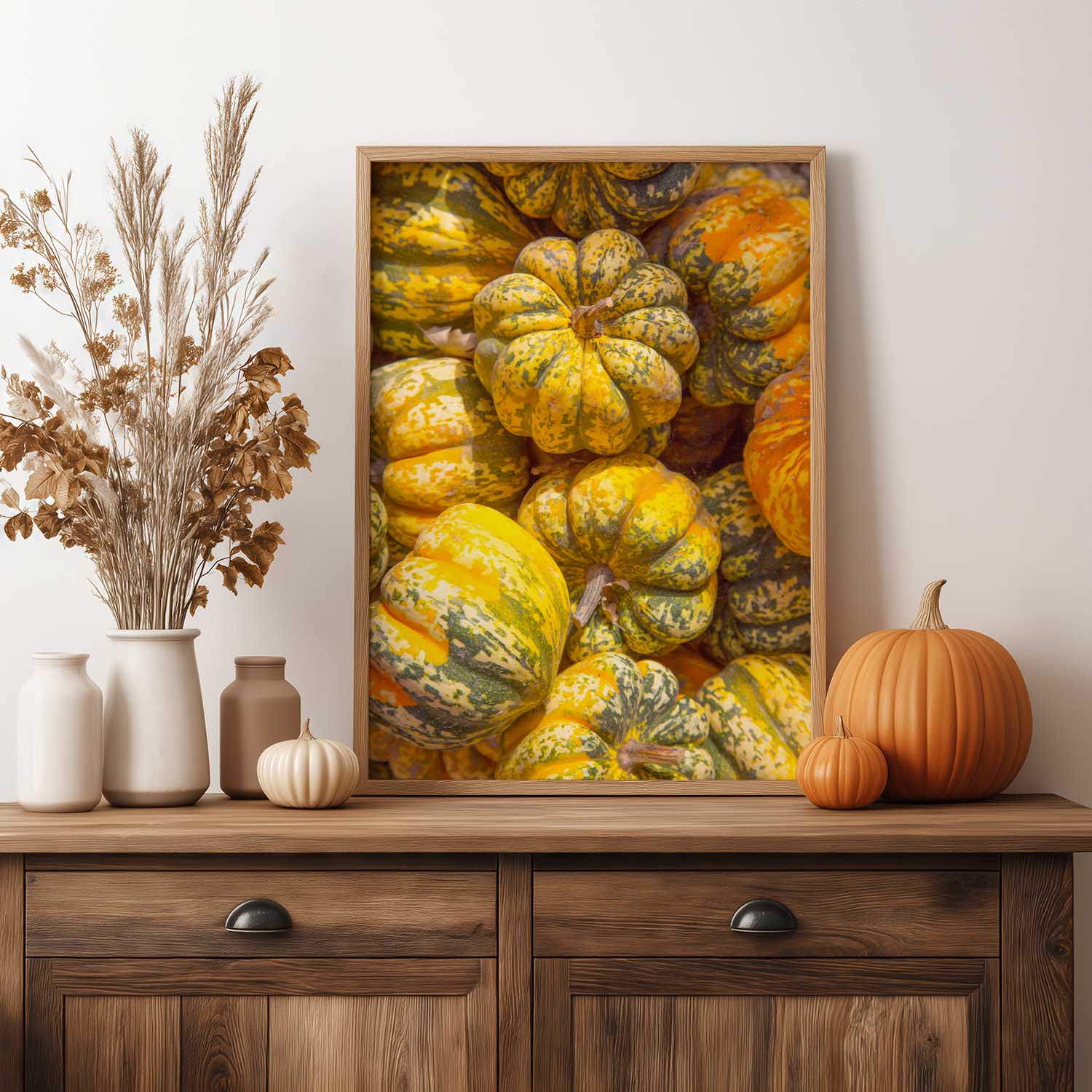 Framed artwork of pumpkins on a wooden console table with decorative items.