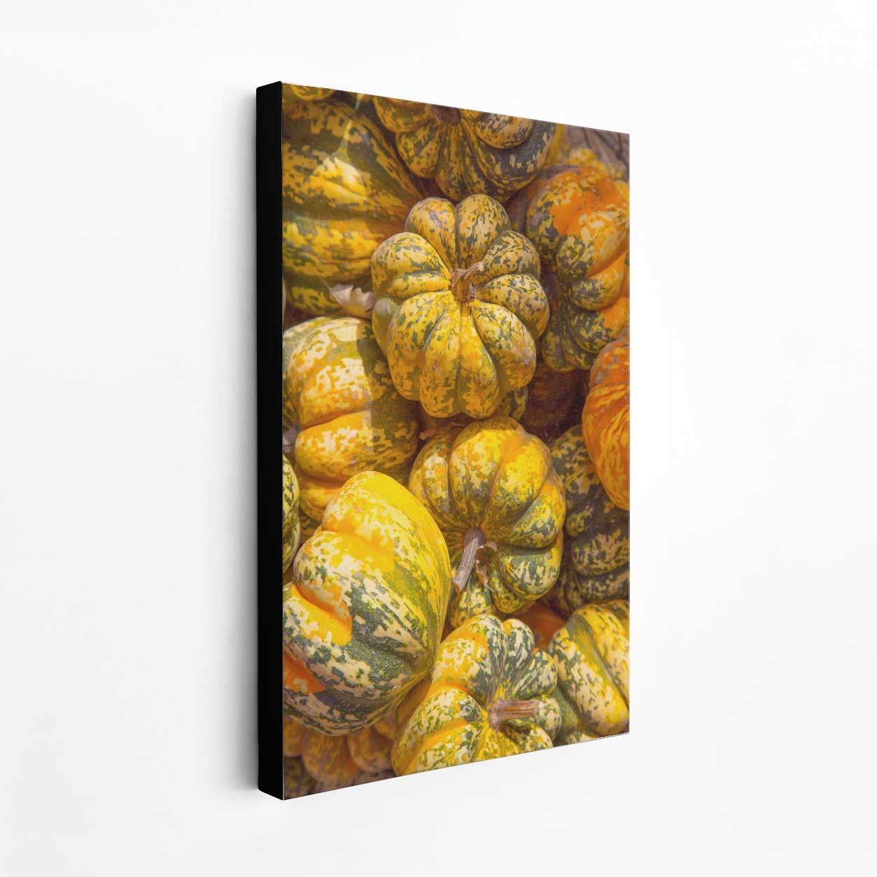 Canvas print of yellow and orange carnival pumpkins on a white wall.