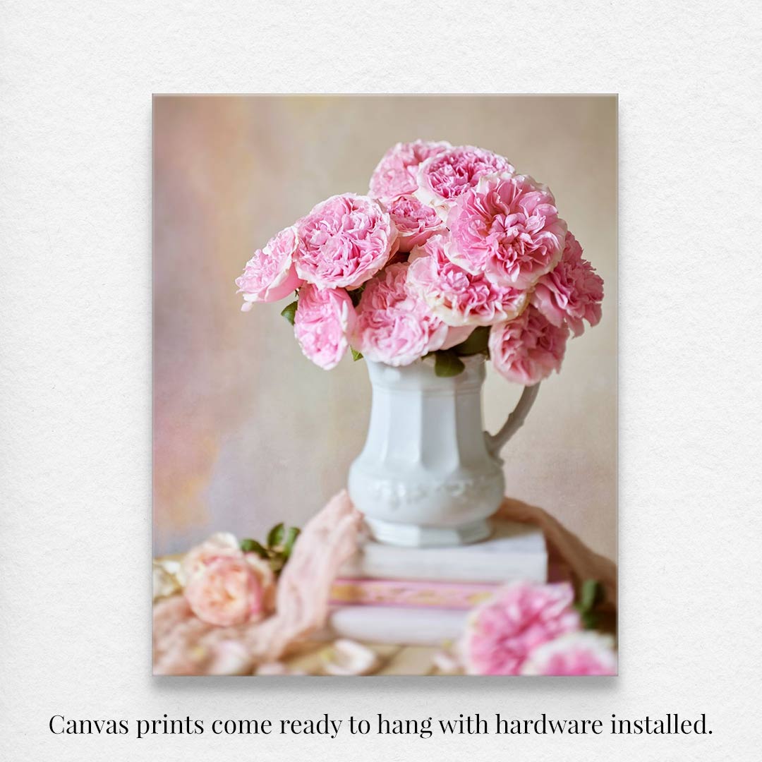 The Miranda Muse canvas features a bouquet of David Austin roses in a white jug on books, with a soft-focus backdrop. It comes ready to hang with hardware installed.