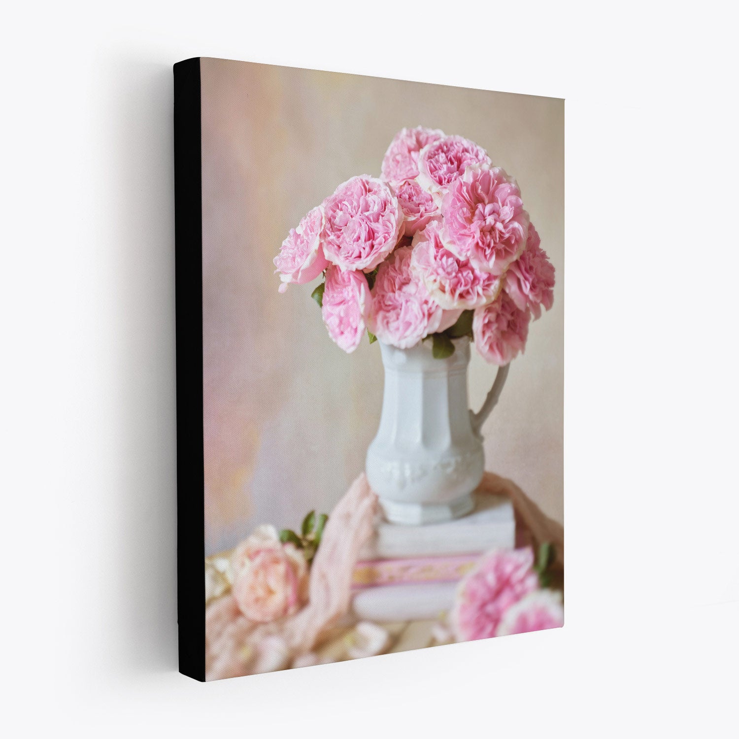 Side view of the Miranda Muse canvas wall art showcasing Miranda roses in a white water pitcher placed on a few books. The canvas has a 1.5-inch black edge, producing a floating effect.