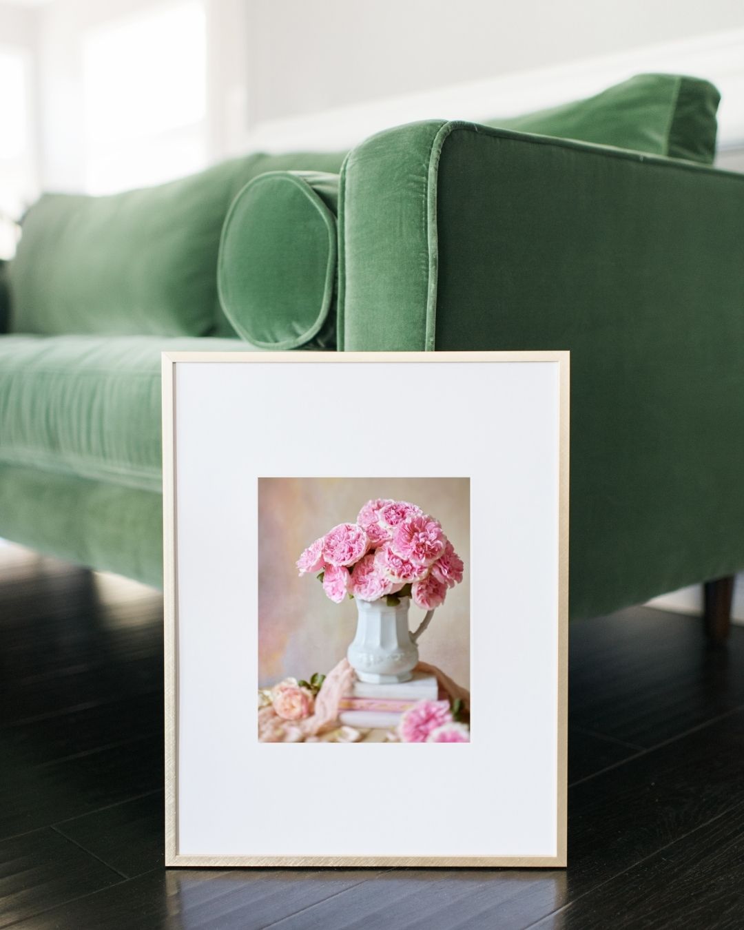 Image of the Miranda Muse paper print framed and leaning against a green velvet couch. 