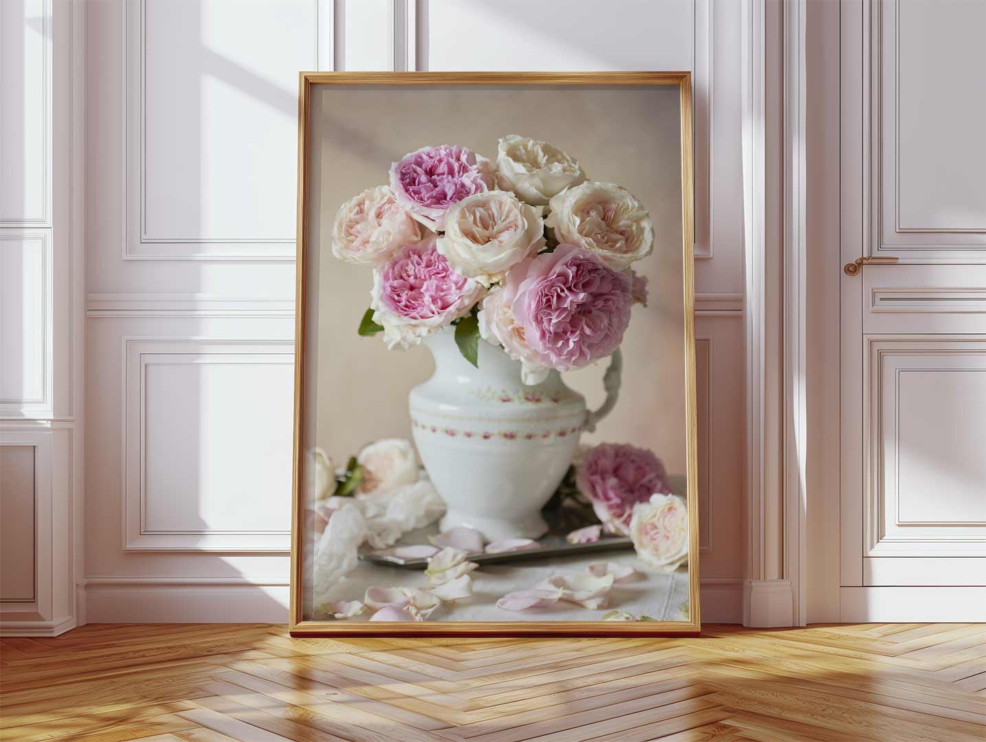 This framed Romance in Bloom canvas features pink and white David Austin roses in a decorative vase. The canvas leans against a wall in a well-lit room with wood flooring and white paneling.