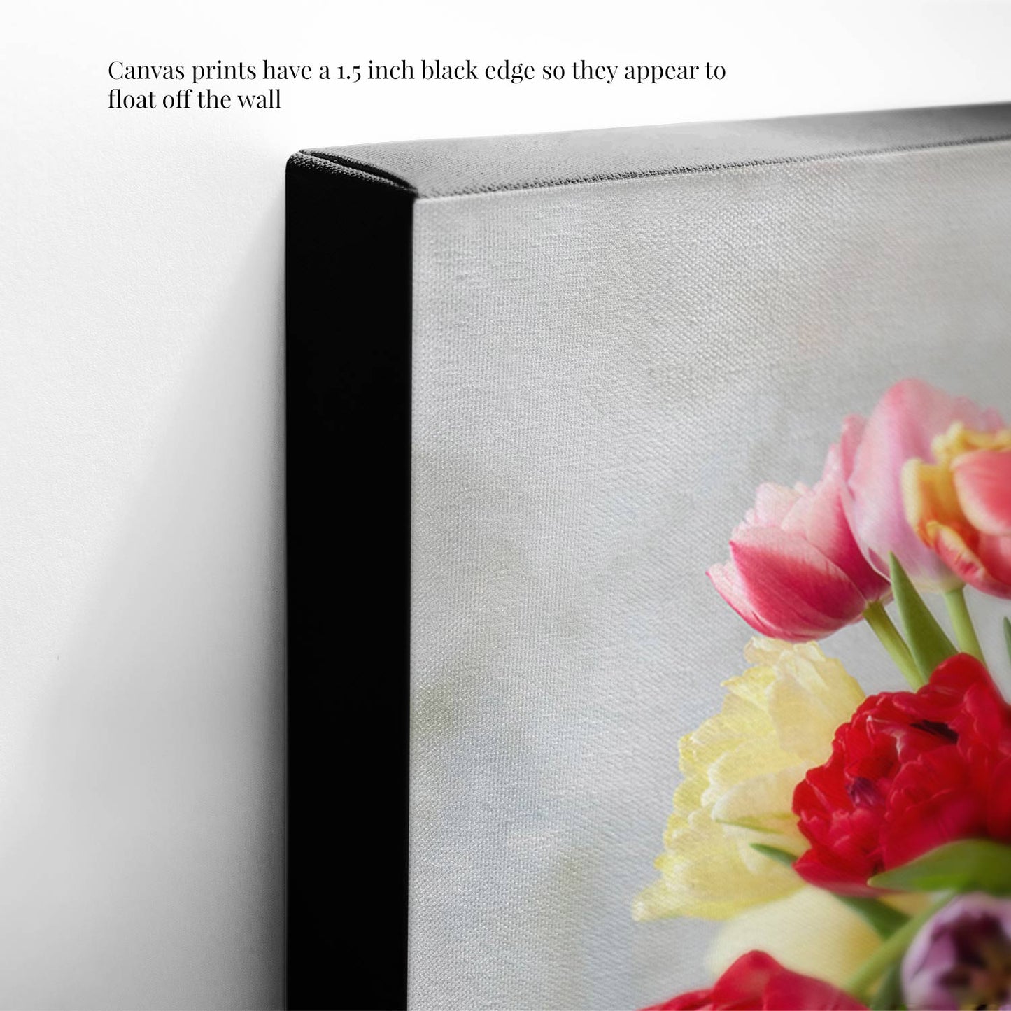 A close-up of the Spring Symphony canvas print reveals a vibrant floral image with red, pink, and yellow flowers. The artwork features a 1.5-inch black edge, creating a floating effect when displayed on the wall.