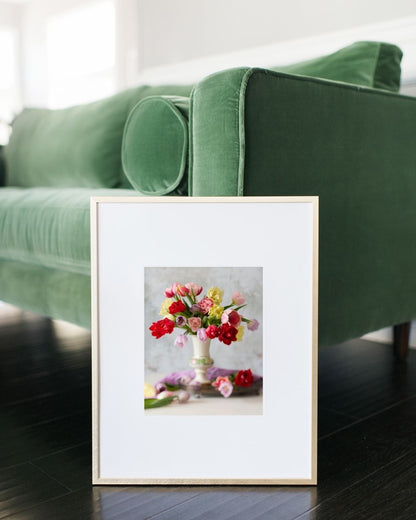 Image of the Spring Symphony paper print framed and leaning against a green velvet couch. 