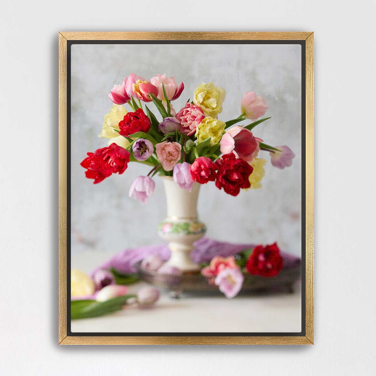 A framed image of a vase filled with a variety of colorful flowers, including red, pink, yellow, and white blooms, placed on a table.