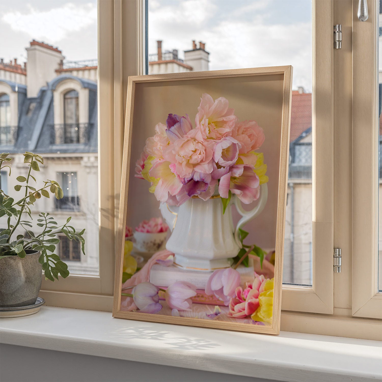 Teapot of Bloom canvas print framed on a windowsill leaning against the window with buildings outside.