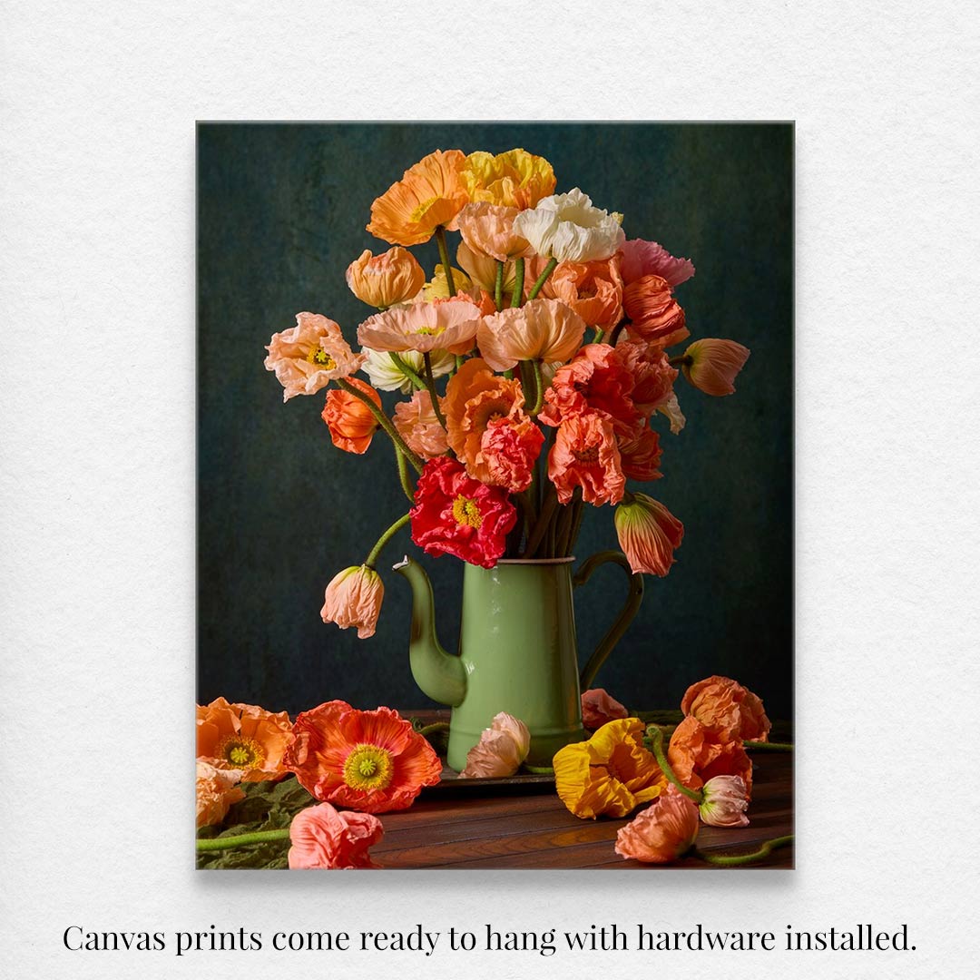 The Poppy Sisters Portraits - 3 Piece canvas print showcases a vibrant bouquet of orange, pink, and peach flowers in a green teapot vase against a dark background, complemented by artfully arranged flowers on a wooden surface, with hardware installed for your convenience.