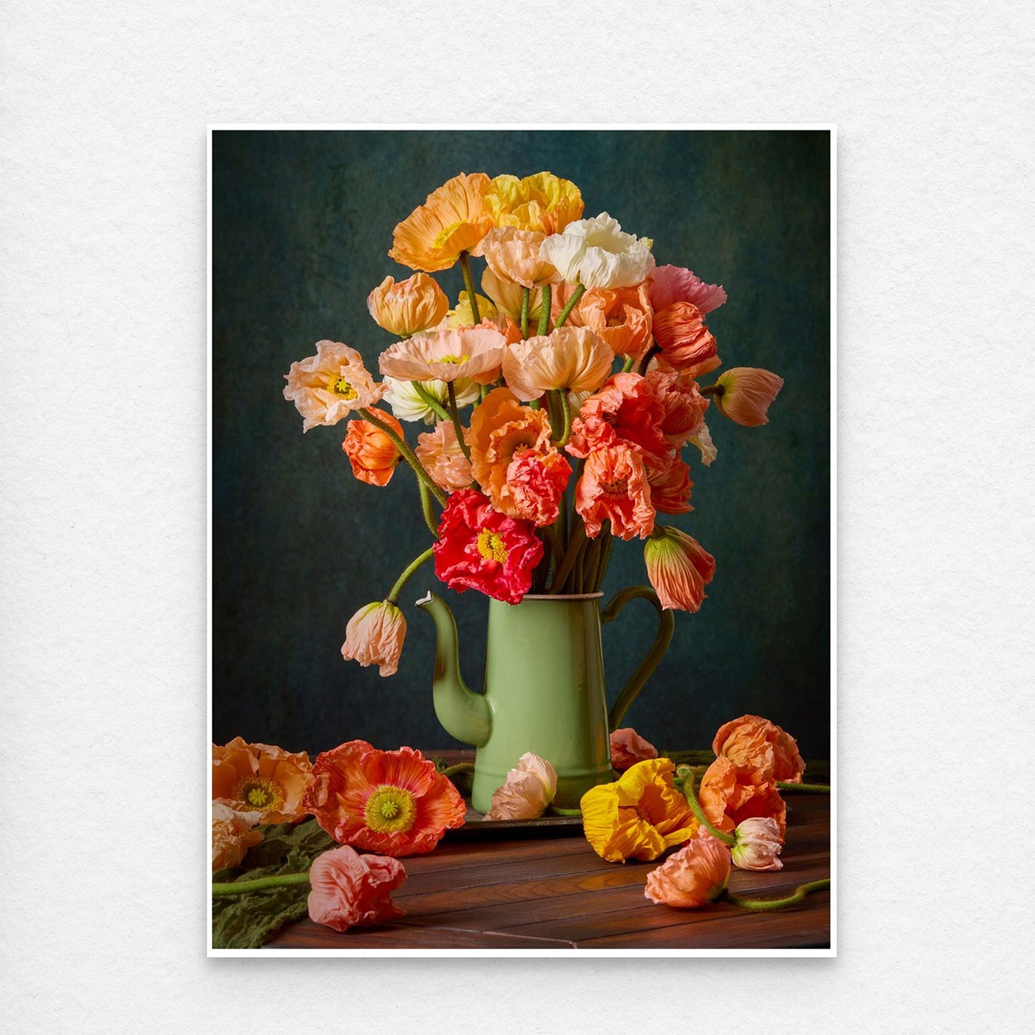 The Poppy Sisters Portraits - 3 Piece showcases a lively mix of Italian pastel poppies in orange, pink, yellow, and red. They rest in a vintage green vase on a wooden table with scattered blooms against a dark, textured backdrop.