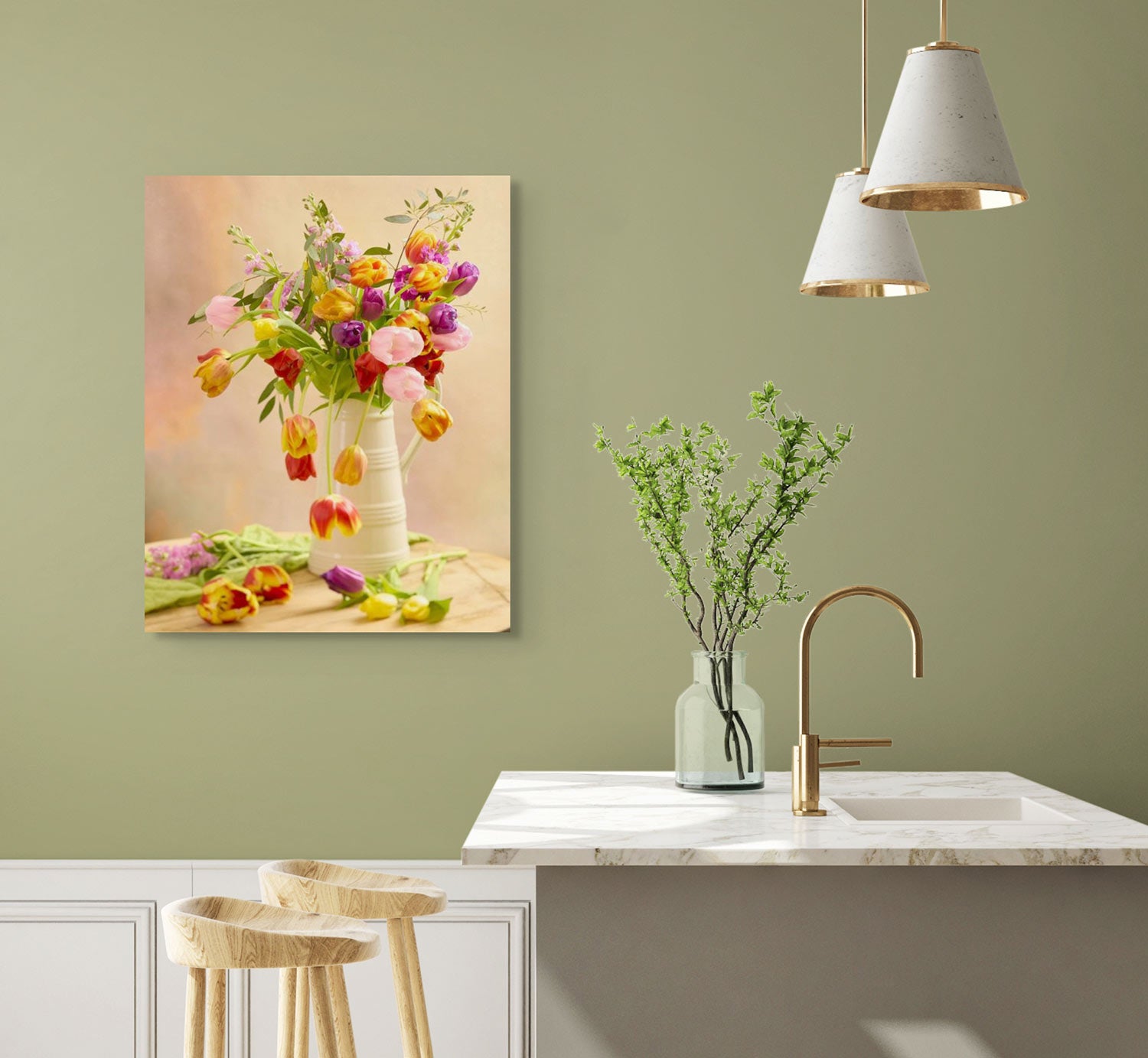 A modern kitchen showcases a marble counter with two wooden stools and a gold faucet. A vase with green branches sits on top, while the Tulip Cascade canvas, depicting vibrant flowers in a white vase, decorates the olive-green wall. Two hanging lamps provide warm illumination.