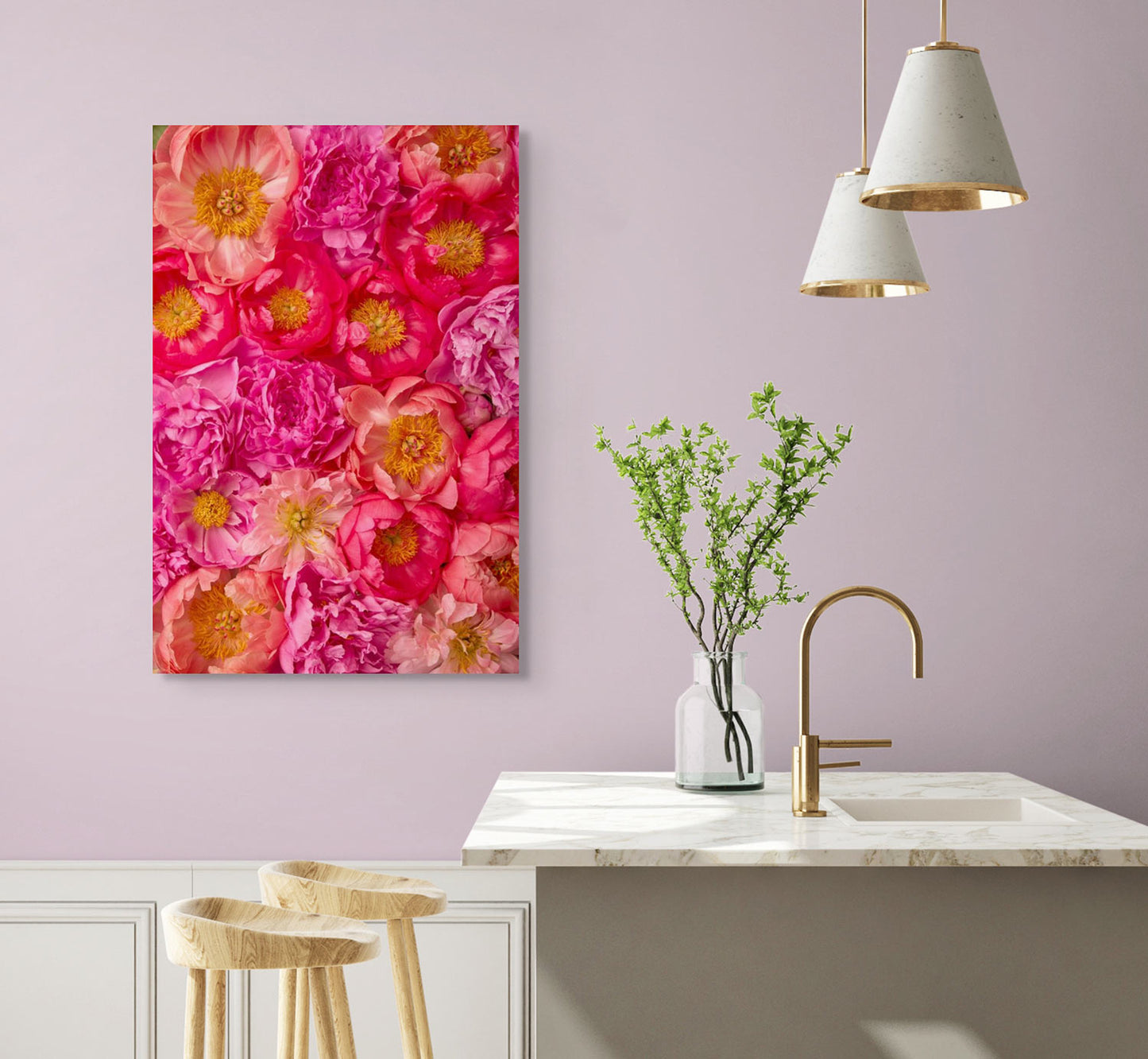 A modern kitchen with light pink walls includes a white countertop, wooden stools, and a vase with green branches. Enhanced by vibrant wall art of pink and orange blossoms titled Peony Bed - Radiant Dreams.