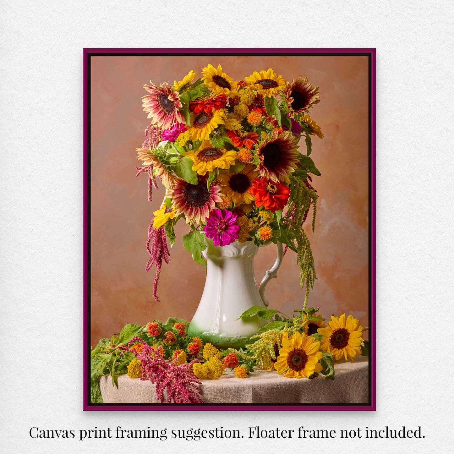 The canvas Golden Fiesta features a vibrant floral arrangement of sunflowers and colorful blooms in a white vase set against a warm brown backdrop, framed by a deep purple border. Text suggests canvas print framing; floater frame not included.