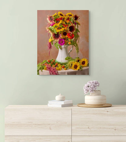 A light wooden dresser with books and a small flower vase sits against a light green wall. Above it hangs Golden Fiesta, a stunning canvas showcasing a bouquet of brightly colored sunflowers in a white vase.