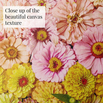 Close-up of a vibrant floral pattern on the Zinnia Bed - Dawn To Dusk canvas. Pink, yellow, and peach flowers with visible texture highlight the zinnias colors and details. Text overlay: Close up of the beautiful canvas texture.