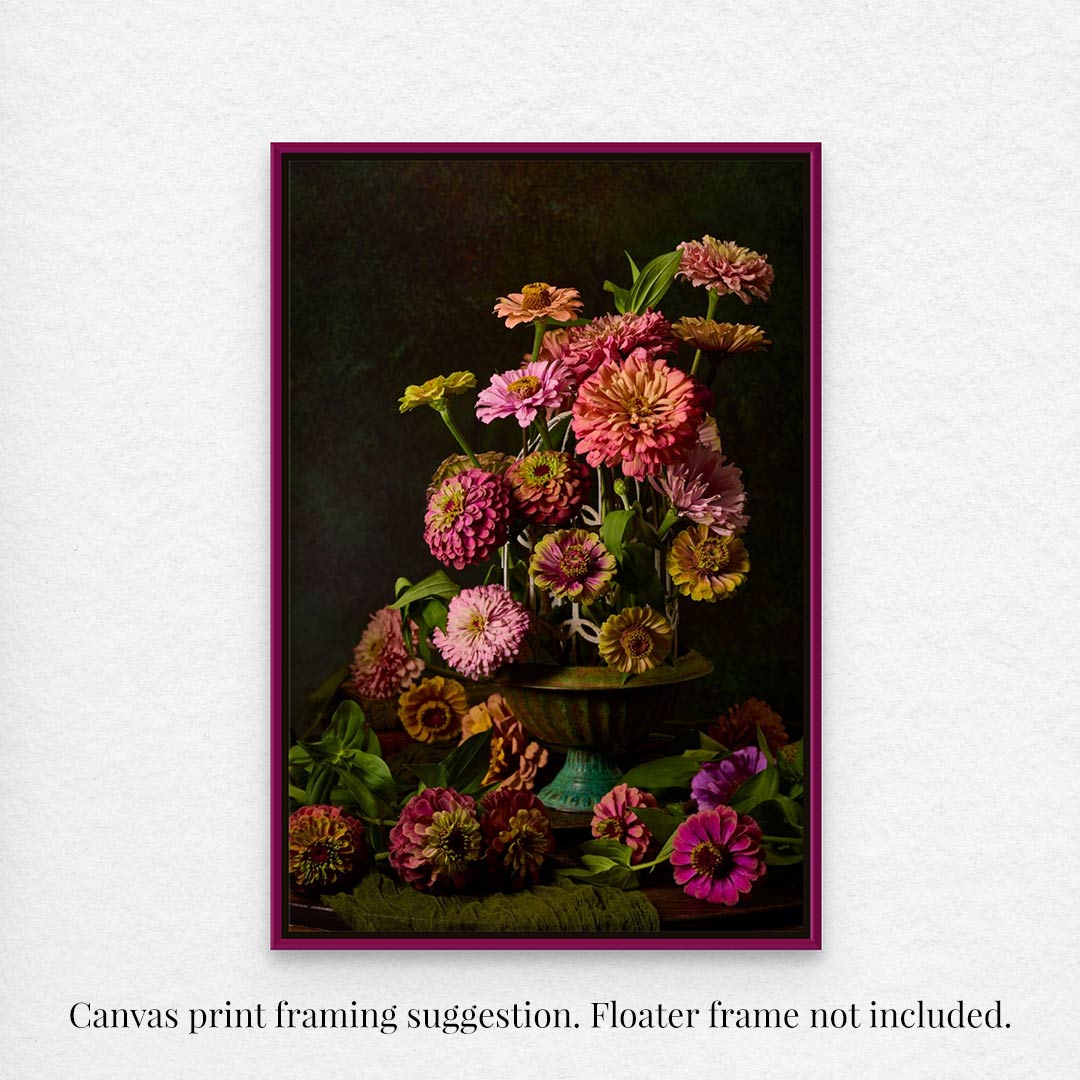 The framed Petals In Flight showcases a vibrant floral arrangement of zinnias in pink, orange, and purple against a dark backdrop. Some blooms are scattered around. Text notes floater frame not included.