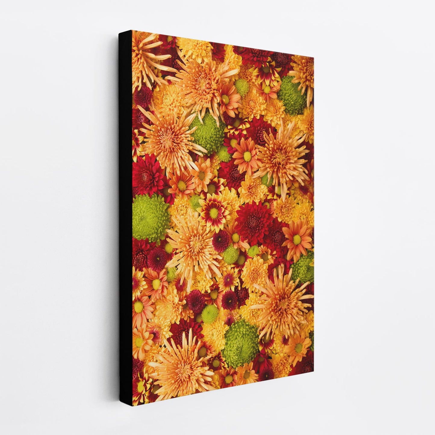 The Chrysanthemum Bed - Autumn's Embrace canvas wall art showcases vibrant chrysanthemums in orange and red with green accents on a white wall, forming a dense, lively pattern that captures autumnal warmth and seasonal beauty. The side view of the canvas shows the black edge, making it appear as if it floats off the wall.