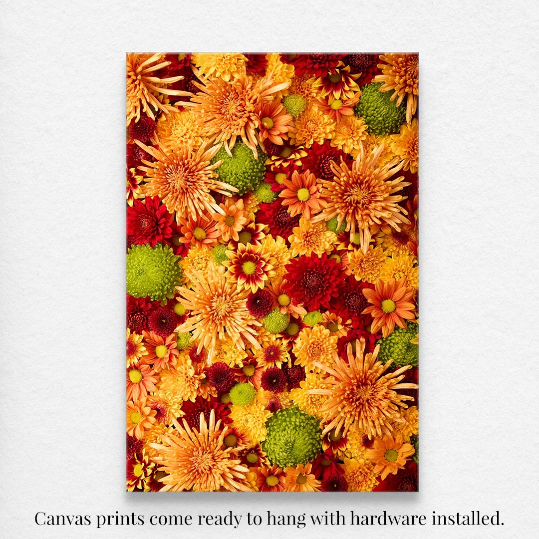 Chrysanthemum Bed - Autumns Embrace: A vibrant canvas wall art showcases a dense floral collection of autumn flowers in orange, red, yellow, and green hues on a white wall. Comes ready to hang with hardware installed.