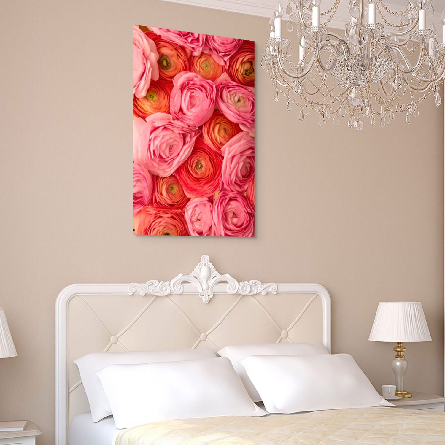 Elegant bedroom with an antique, white upholstered headboard and two bedside lamps. The Layers of Love large canvas featuring pink, coral, and orange ranunculus hangs above the bed, while a crystal chandelier adds luxury to the room.