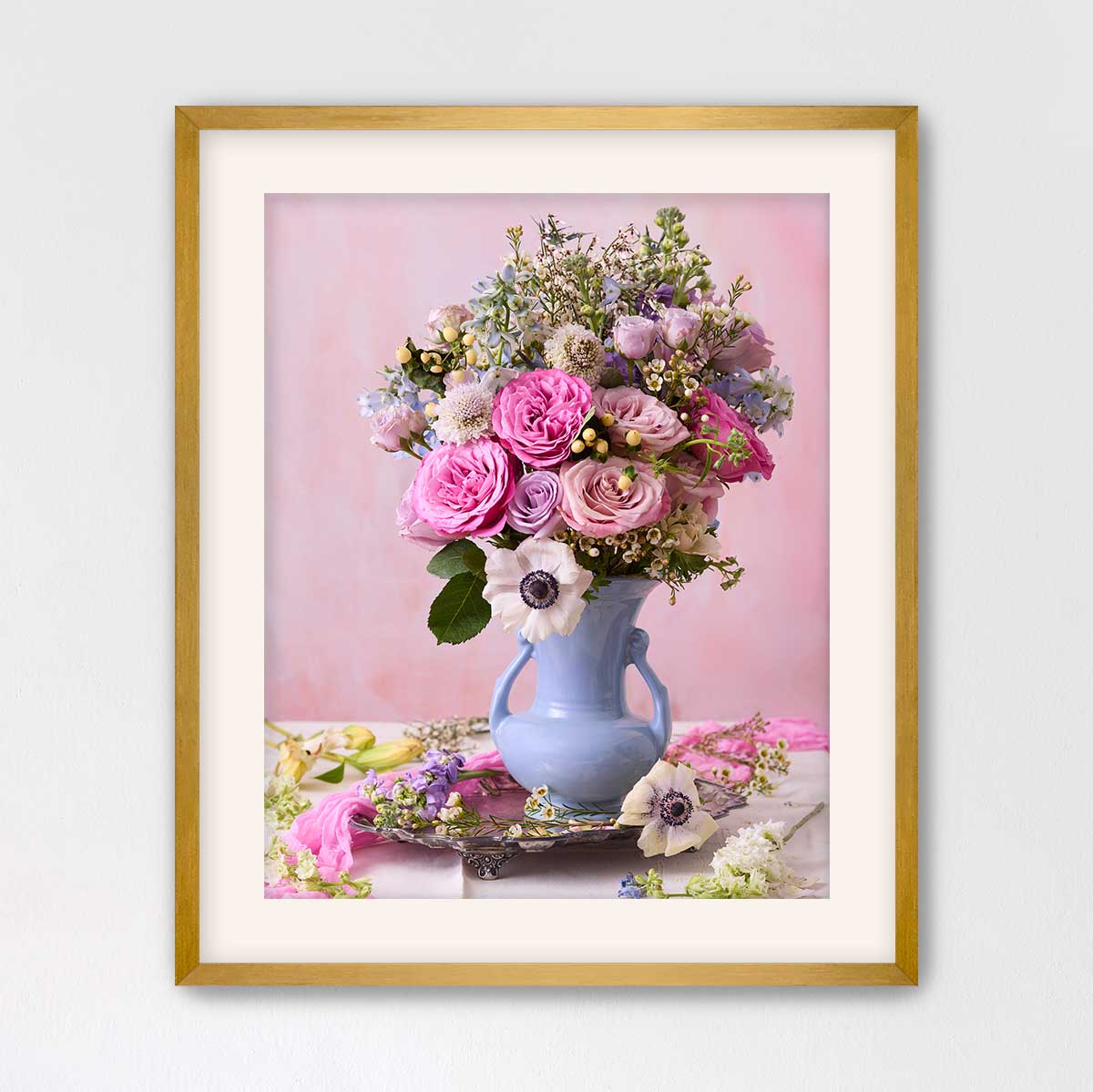 A framed image of a vase filled with a variety of colorful flowers, including pink roses, white lilies, and purple and white flowers, set against a pink background.
