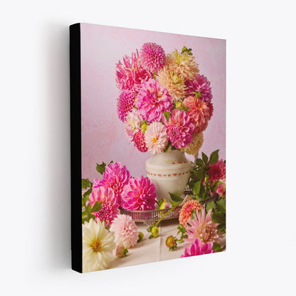 Side view of the canvas print Summer Afternoon featuring a vintage porcelain pitcher filled with vibrant pink, orange, and cream dahlias, with more dahlias elegantly arranged on the table with a soft pink background. The canvas is showing black wrapped sides making it appear to be floating off the wall.