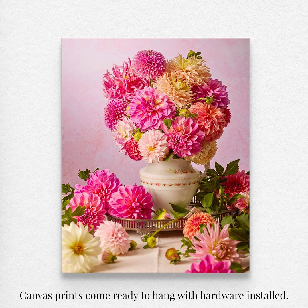 Experience Summer Afternoon: a canvas print of pink, orange, and cream dahlias in a vintage pitcher, surrounded by flowers and greenery on a pastel background. Comes ready to hang with hardware installed.