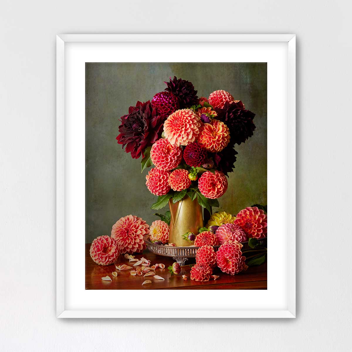 A framed image of a vase filled with a variety of colorful dahlias, including red, pink, and orange flowers, placed on a wooden surface.