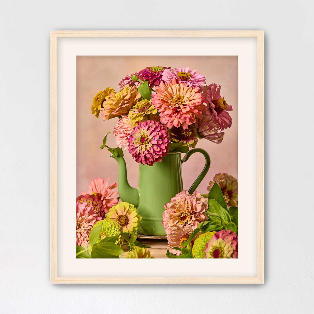 A framed image of a green teapot filled with a vibrant bouquet of pink and yellow flowers, creating a colorful and lively still life composition.