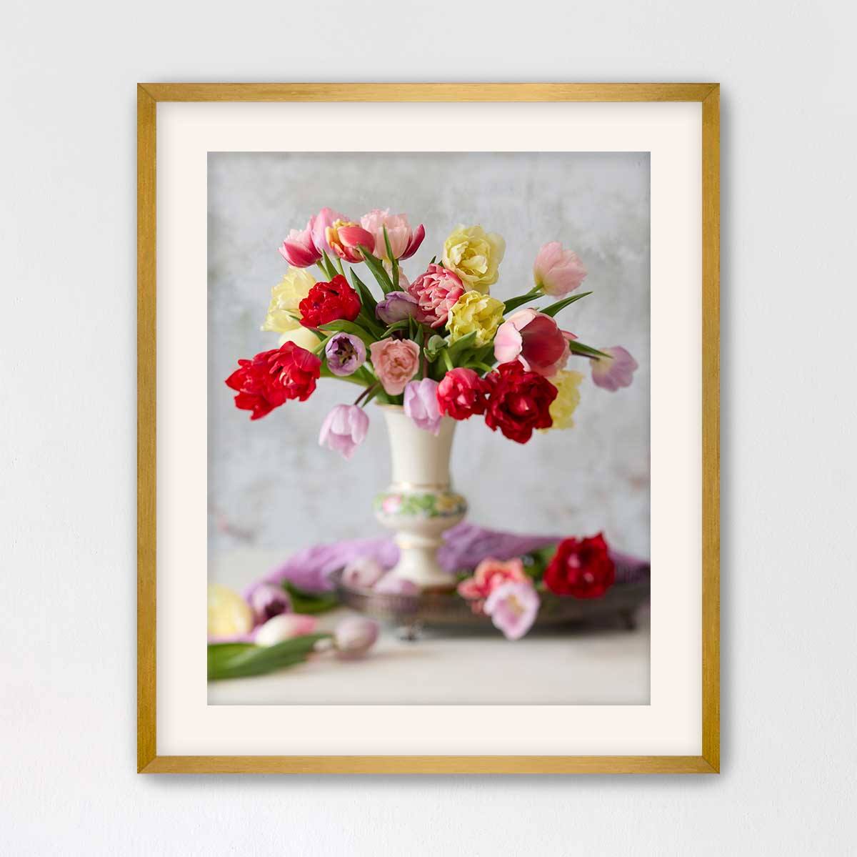 A framed photograph of a vase filled with a variety of colorful flowers, including red, pink, yellow, and purple blooms, set against a neutral background.