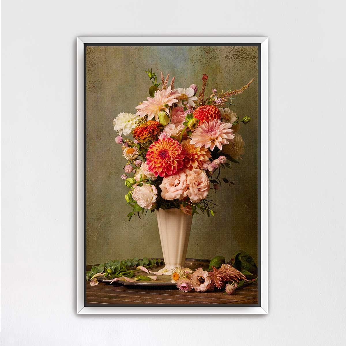 A framed image of a vase filled with a vibrant bouquet of flowers, including dahlias, roses, and other blooms, placed on a wooden surface.