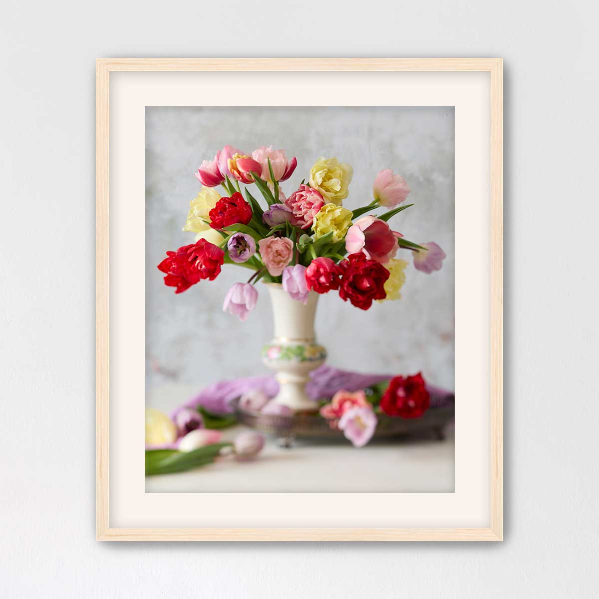 A framed photograph of a vase filled with a variety of colorful flowers, including red, pink, yellow, and purple blooms, set against a neutral background.