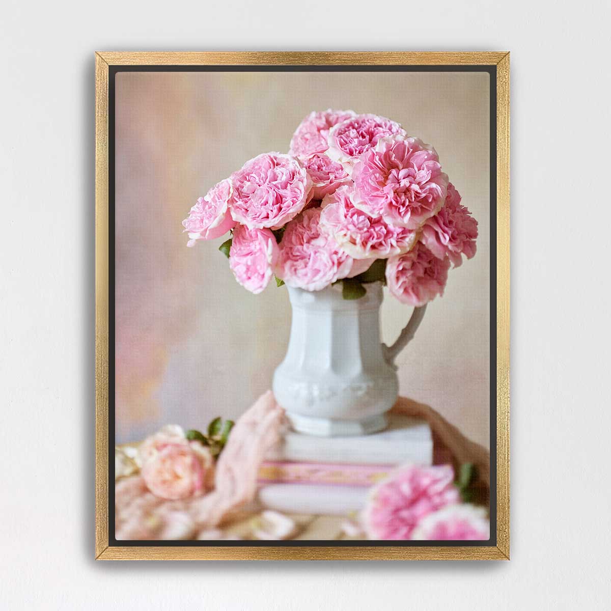 A white vase filled with pink carnations sits on top of a stack of books, creating a charming and elegant still life composition.