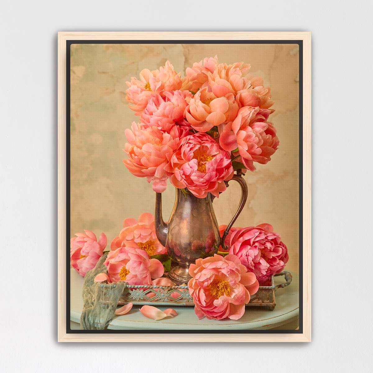A vase filled with vibrant pink peonies sits on a table, surrounded by additional peonies.