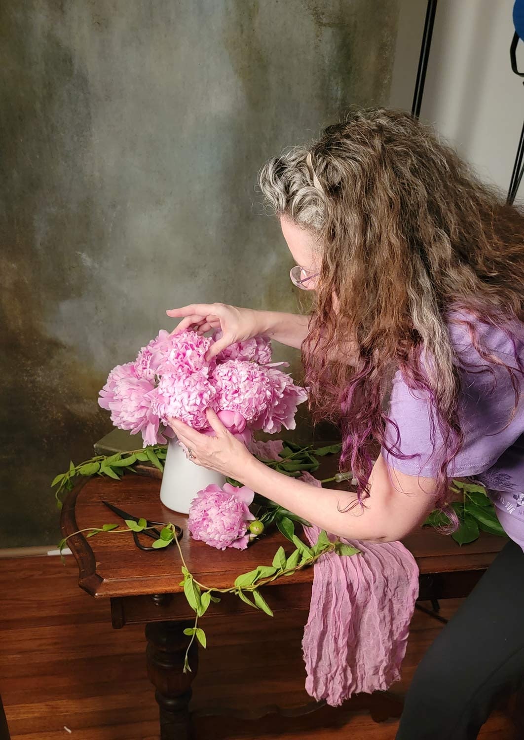 Christina Peters in her studio styling on set with pink peonies