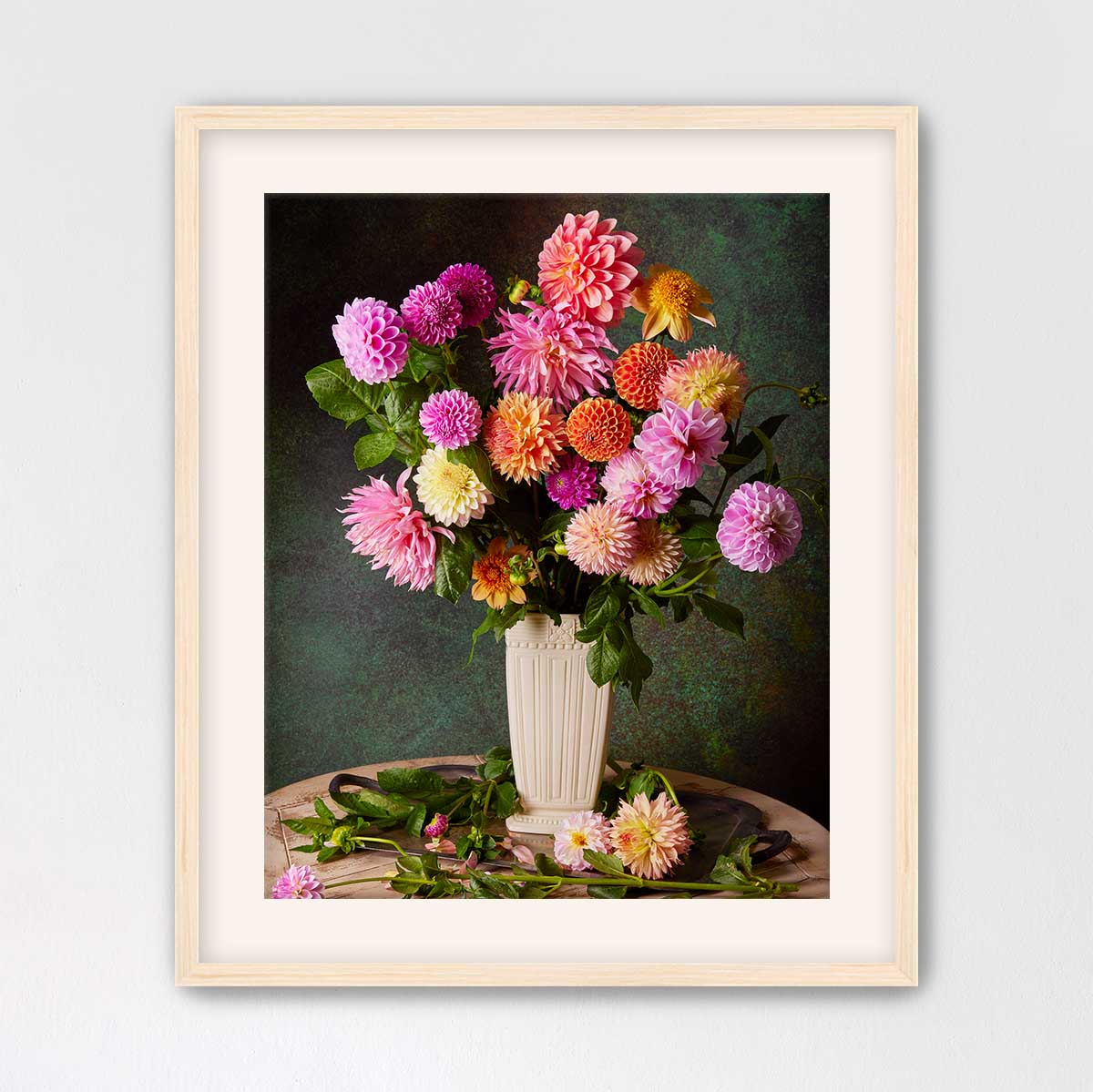 A framed image of a vase filled with a variety of colorful dahlias, including pink, orange, and yellow flowers, set against a dark green background.