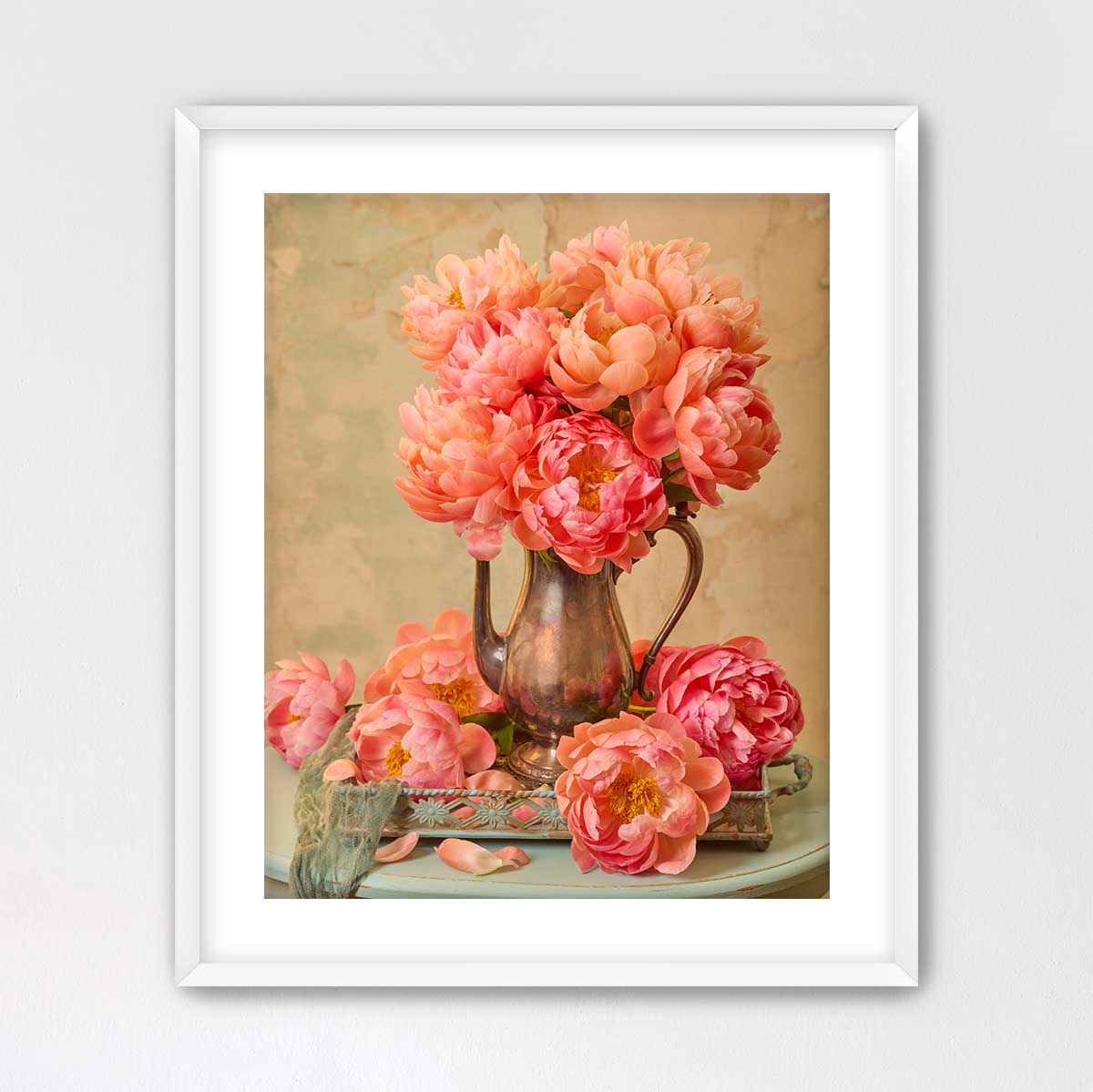 A framed image of a vase filled with vibrant pink peonies, placed on a small table.