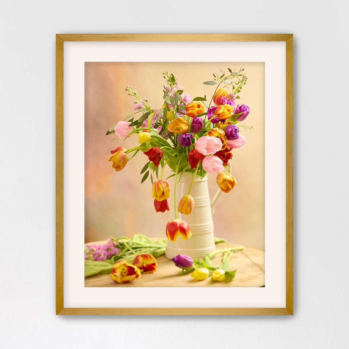 A framed photograph of a vase filled with a variety of colorful tulips, including red, pink, yellow, and purple flowers, placed on a wooden surface.